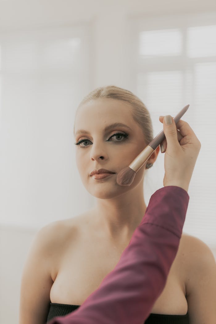 Makeup artist applying blush to woman